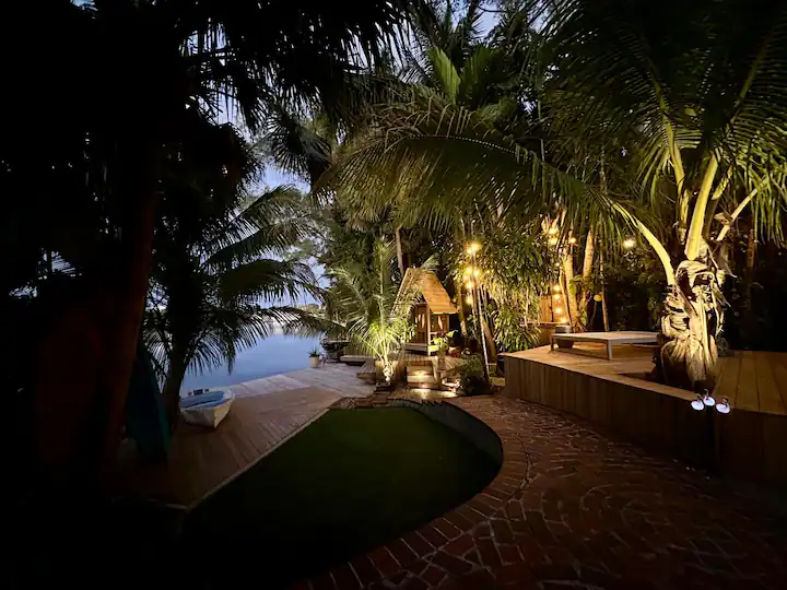 The garden and lake at night, lit by string lights