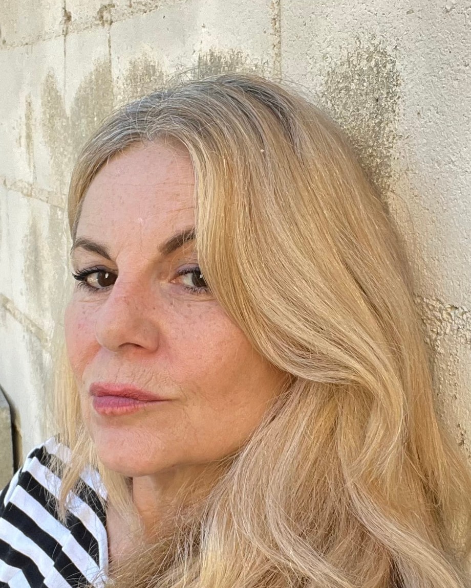 Deborah Jaffe seated against a sunlit stone wall in a striped shirt